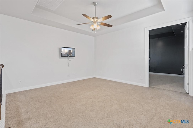 carpeted empty room featuring a tray ceiling and ceiling fan