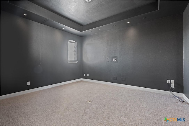 carpeted empty room with a raised ceiling and a textured ceiling