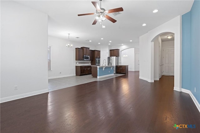 unfurnished living room featuring ceiling fan with notable chandelier, dark hardwood / wood-style flooring, and sink