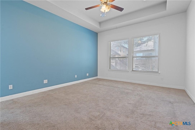 spare room with a raised ceiling, ceiling fan, and carpet floors