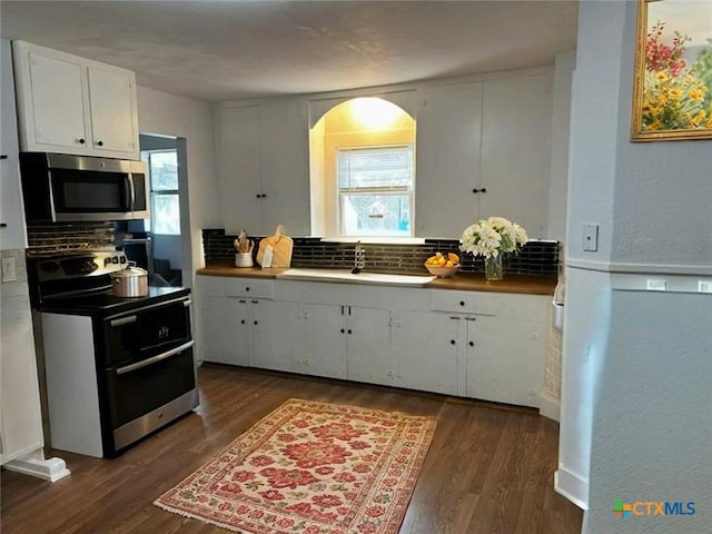 212 Duggan St, Seguin, TX 78155 - kitchen featuring appliances with stainless steel finishes, backsplash, white cabinetry, dark wood finished floors, and a textured wall