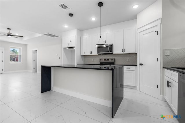 kitchen featuring white cabinetry, hanging light fixtures, appliances with stainless steel finishes, ceiling fan, and backsplash