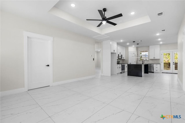 unfurnished living room featuring a raised ceiling, ceiling fan, and french doors