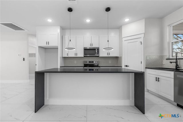 kitchen featuring white cabinetry, stainless steel appliances, decorative light fixtures, and sink