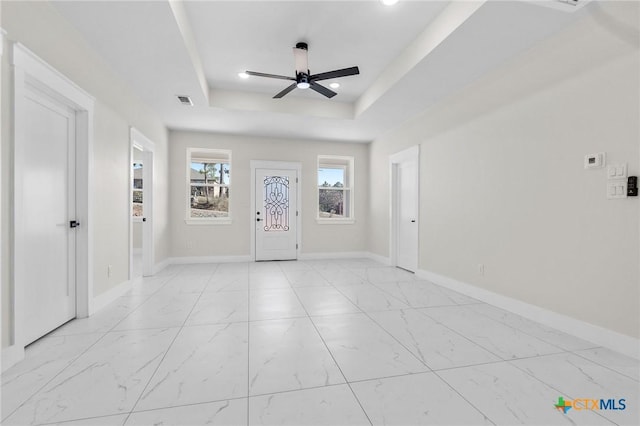 entryway with a raised ceiling and ceiling fan