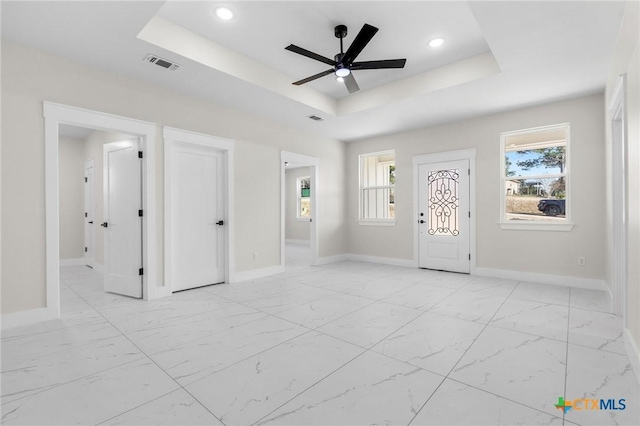 entryway with ceiling fan and a tray ceiling