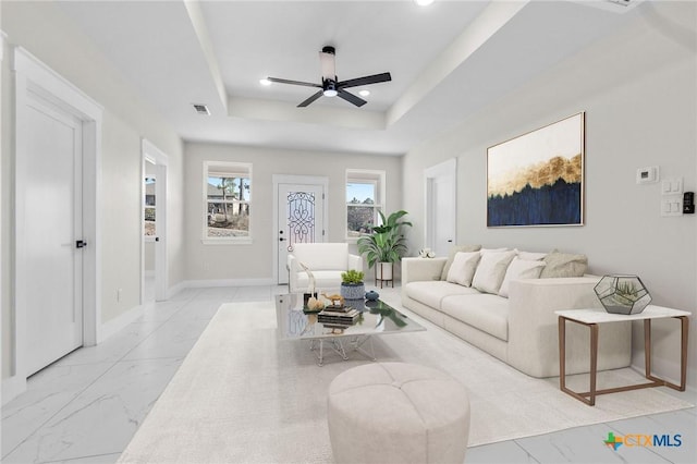 living room with ceiling fan and a raised ceiling