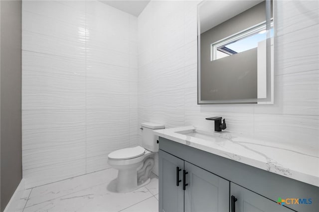 bathroom featuring vanity, tile walls, and toilet