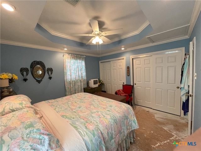 bedroom featuring two closets, a tray ceiling, ceiling fan, and crown molding