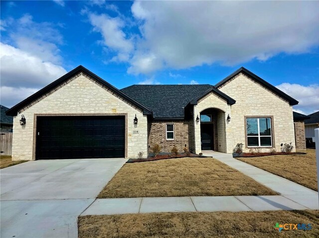 french country style house with a front lawn and a garage