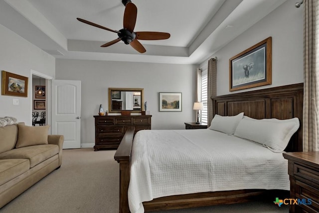 bedroom with light carpet, a tray ceiling, and ceiling fan