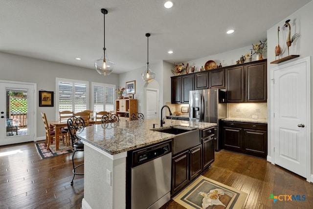 kitchen with sink, stainless steel appliances, dark wood-type flooring, and an island with sink