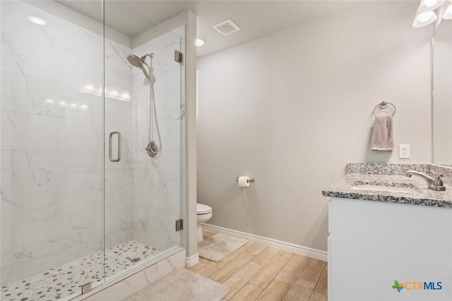 bathroom featuring toilet, a stall shower, wood tiled floor, and visible vents