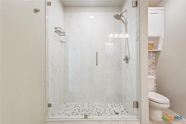 bathroom with baseboards, toilet, and a marble finish shower