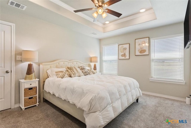 bedroom with a tray ceiling, baseboards, visible vents, and carpet flooring