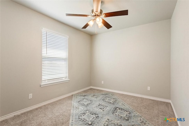 carpeted empty room with a ceiling fan and baseboards