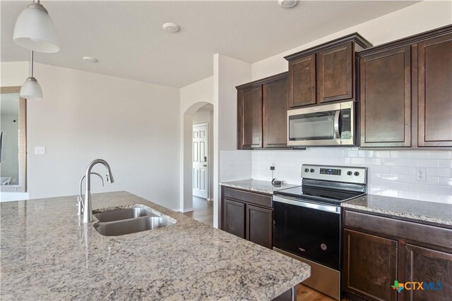 2215 Lucrezia Ct, Harker Heights, TX 76548 - kitchen featuring light stone counters, arched walkways, stainless steel appliances, backsplash, and a sink