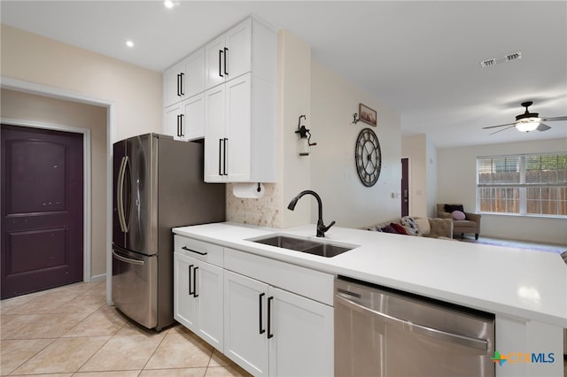 kitchen with tasteful backsplash, appliances with stainless steel finishes, open floor plan, a sink, and a peninsula