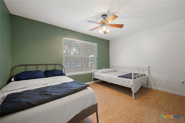 bedroom featuring ceiling fan, baseboards, and wood finished floors