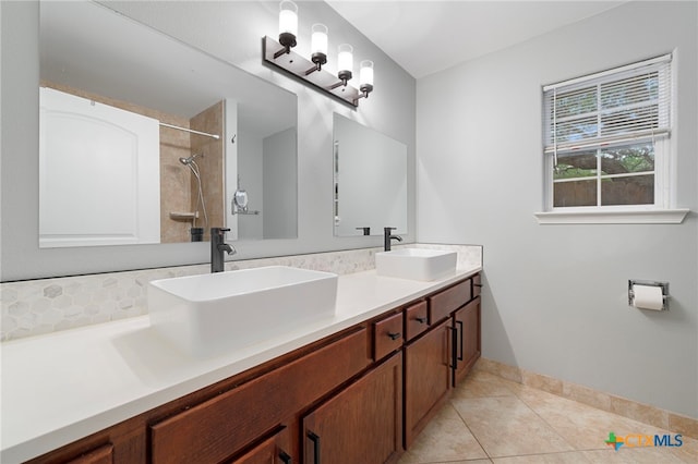 bathroom with double vanity, tiled shower, a sink, and tile patterned floors