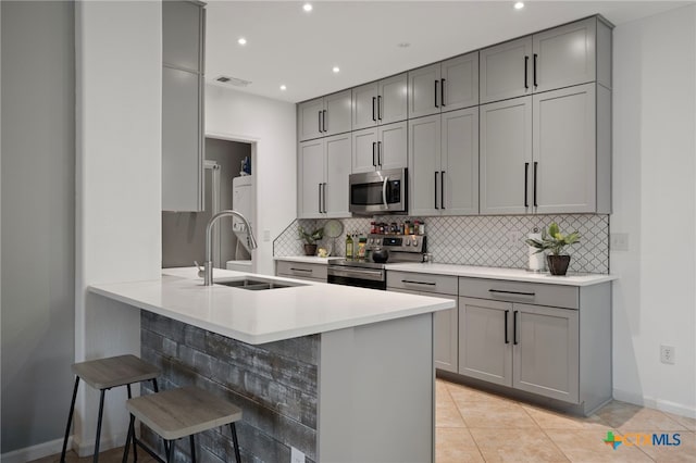 kitchen featuring visible vents, decorative backsplash, appliances with stainless steel finishes, gray cabinets, and a sink