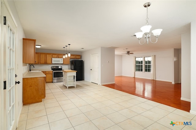 kitchen featuring black fridge, light wood-type flooring, electric stove, hanging light fixtures, and a center island