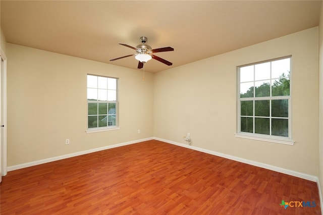 spare room featuring a wealth of natural light, hardwood / wood-style flooring, and ceiling fan