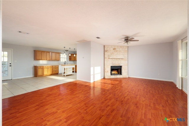 unfurnished living room featuring a fireplace, light hardwood / wood-style flooring, and ceiling fan