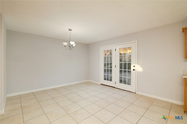 empty room featuring a notable chandelier and light tile patterned floors