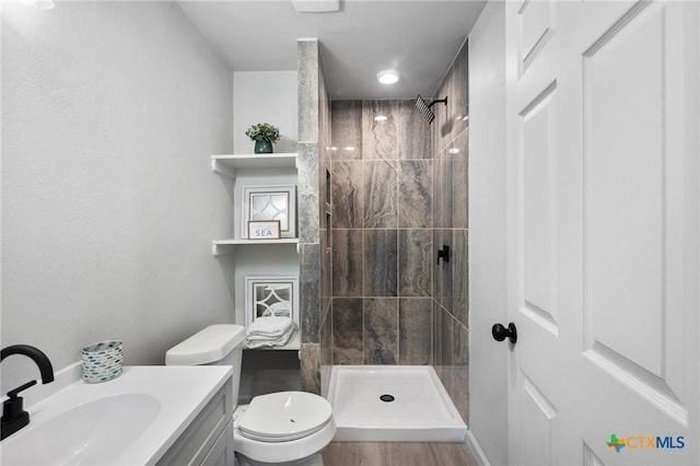 2603 Lone Tree Rd, Victoria, TX 77901 - bathroom featuring a tile shower, toilet, vanity, and wood finished floors