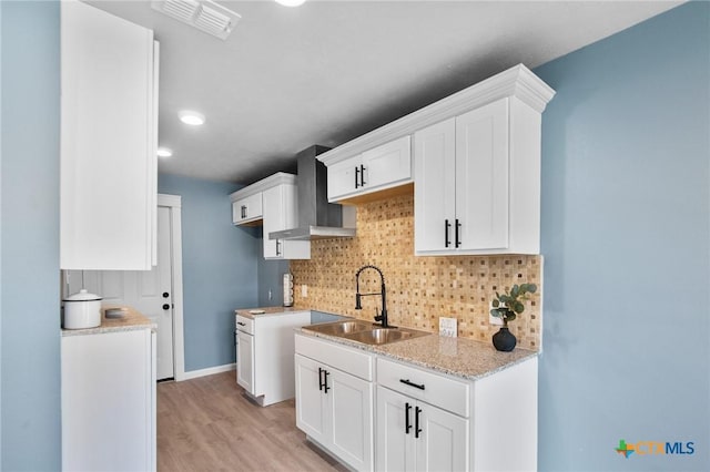 2603 Lone Tree Rd, Victoria, TX 77901 - kitchen with wall chimney exhaust hood, a sink, decorative backsplash, white cabinetry, and light wood-type flooring