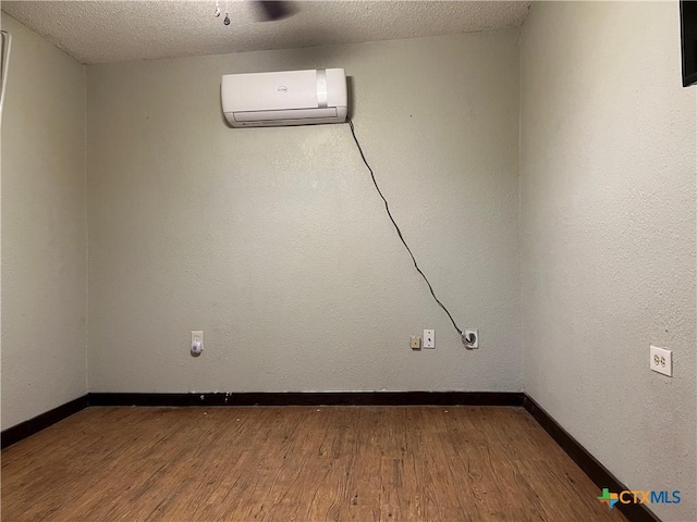 spare room with a wall unit AC, ceiling fan, wood-type flooring, and a textured ceiling