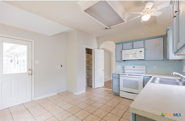 kitchen with arched walkways, light countertops, decorative backsplash, a sink, and white appliances