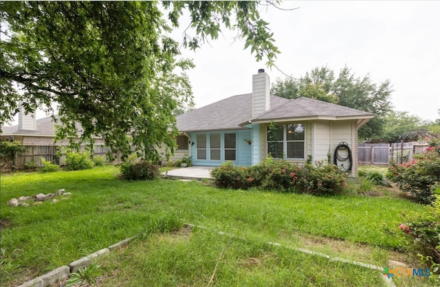 back of property with a chimney, fence, a patio, and a yard