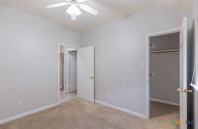 unfurnished bedroom featuring a walk in closet, a closet, light carpet, ceiling fan, and baseboards