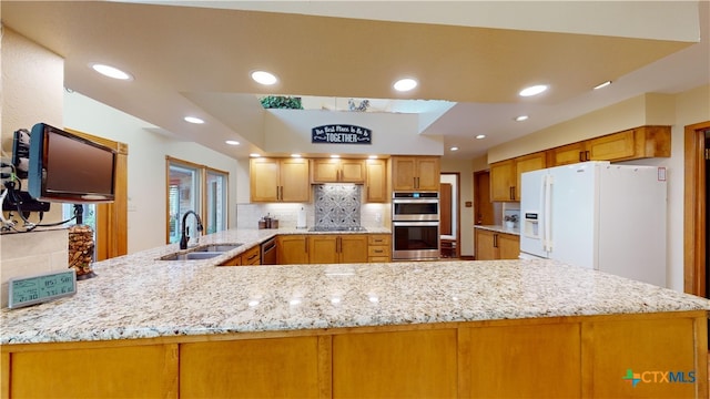 kitchen with backsplash, sink, light stone countertops, appliances with stainless steel finishes, and kitchen peninsula