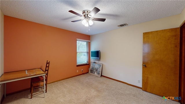 interior space featuring ceiling fan, light colored carpet, and a textured ceiling