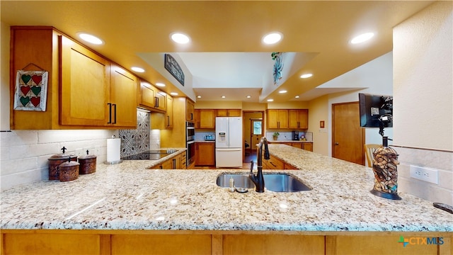 kitchen with kitchen peninsula, black electric stovetop, light stone counters, sink, and white fridge with ice dispenser