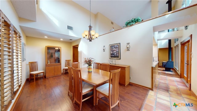 dining area with hardwood / wood-style floors, a notable chandelier, and high vaulted ceiling