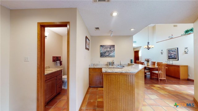 kitchen featuring light stone countertops, a textured ceiling, light tile patterned floors, decorative light fixtures, and a chandelier