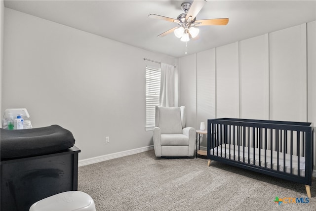 bedroom with carpet flooring, ceiling fan, and a crib