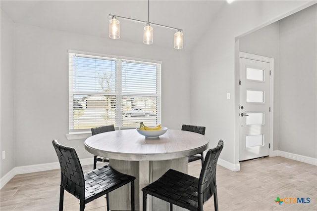 dining room featuring light hardwood / wood-style flooring, lofted ceiling, and a chandelier