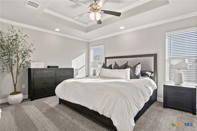 carpeted bedroom featuring multiple windows, ceiling fan, crown molding, and a tray ceiling