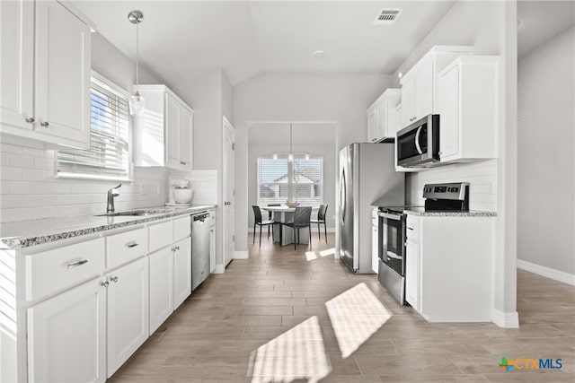 kitchen featuring white cabinets, a wealth of natural light, decorative light fixtures, and stainless steel appliances