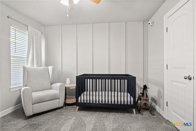 bedroom with a crib, ceiling fan, and carpet