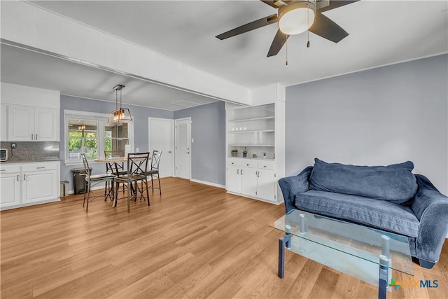 living room with light wood-style flooring, baseboards, and ceiling fan