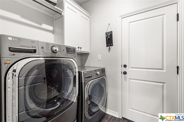 washroom with washing machine and clothes dryer, cabinets, and dark wood-type flooring