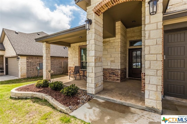 property entrance with brick siding, stone siding, roof with shingles, a garage, and a porch