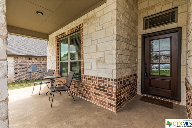 view of exterior entry with a porch and brick siding
