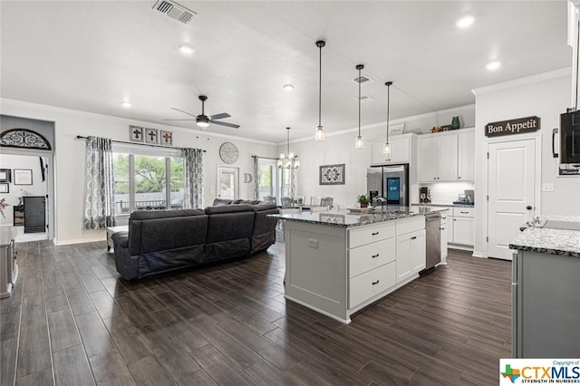 kitchen with appliances with stainless steel finishes, a ceiling fan, open floor plan, light stone counters, and white cabinetry